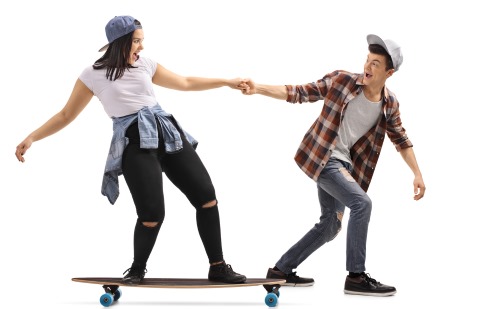 スケートボードをする少女を引っ張る少年