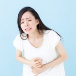 お腹を抱えて苦しむ女性